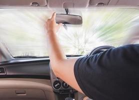 un homme ajuste le rétroviseur en conduisant une voiture. effet de flou de mouvement est appliqué à cette photo. photo