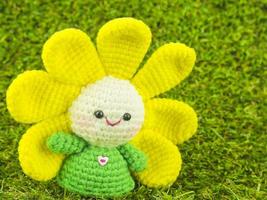 Happy baby flower, poupée au crochet fait main sur fond d'herbe verte photo