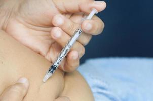 une dame s'injecte de l'insuline dans l'estomac. la photo est mise au point sur la seringue.