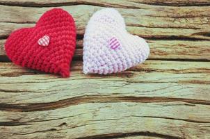 couple de coeur au crochet en rouge et rose sur fond de bois. la photo est centrée sur le coeur rouge.