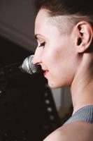 jeune chanteuse de rock avec microphone, souriant et chantant. vue arrière. fermer. femme aux cheveux courts chantant sur une scène. spectacle de musique en direct photo