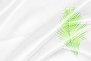 superposition de motifs de feuilles de palmier vert avec texture de tissu blanc arrière-plan flou doux photo