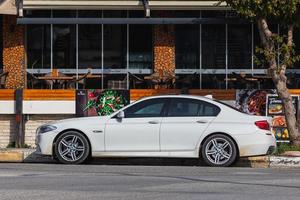 manavgat turquie 05 mars 2022 la série 5 bmw blanche est garée dans la rue par une chaude journée sur fond de construction, boutique photo