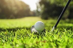 gros plan club de golf et balle de golf sur l'herbe verte avec coucher de soleil photo