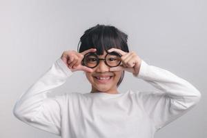 jolie petite fille d'âge préscolaire isolée sur fond de studio gris porter des lunettes regarder la caméra, petit enfant essayer des lunettes chez les opticiens, concept de traitement de correction de la vue des enfants photo