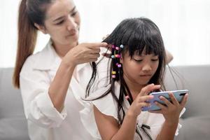 jeune mère asiatique attachant les cheveux de sa fille photo