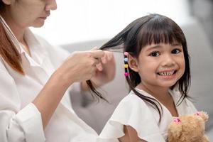 jeune mère asiatique attachant les cheveux de sa fille photo