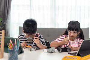 deux enfants asiatiques s'amusant à apprendre à coder ensemble, à apprendre à distance à la maison, à la science des tiges, à l'enseignement à domicile, à la distanciation sociale amusante, à l'isolement, au nouveau concept normal photo