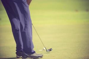 joueur de golf au green frappant la balle dans un trou.couleur vintage photo