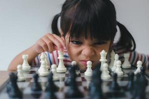 petite fille asiatique jouant aux échecs à la maison.une partie d'échecs photo