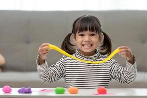 la petite fille apprend à utiliser de la pâte à modeler colorée dans une pièce bien éclairée photo