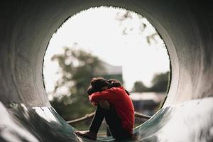 une fille asiatique solitaire assise seule dans le parc, une fille thaïlandaise triste pense quelque chose, un concept de fille triste photo