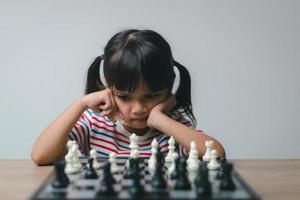 petite fille asiatique jouant aux échecs à la maison.une partie d'échecs photo
