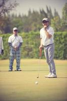 joueur de golf au green frappant la balle dans un trou.couleur vintage photo