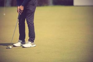 joueur de golf au putting green frapper la balle dans un trou photo