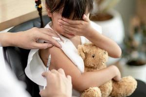 notion de vaccination. femme médecin vaccinant une jolie petite fille à la clinique photo