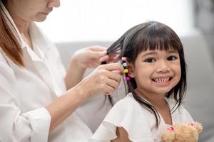 jeune mère asiatique attachant les cheveux de sa fille photo