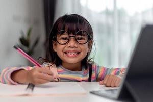 étudiant asiatique fille apprentissage en ligne étude de classe en ligne avec l'enseignant, fille heureuse apprendre la langue anglaise en ligne avec tablette à la maison. nouveau coronavirus normal.covid-19.distanciation sociale. rester à la maison photo