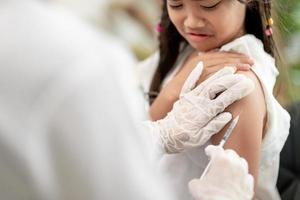 notion de vaccination. femme médecin vaccinant une jolie petite fille à la clinique photo