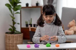 la petite fille apprend à utiliser de la pâte à modeler colorée dans une pièce bien éclairée photo