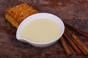 lait concentré dans le bol avec sinnamon et pâtisserie photo