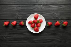 un bol de fraises juteuses rouges sur une table en bois rustique. concept de collations saines et diététiques. photo