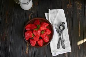 un bol de fraises juteuses rouges sur une table en bois rustique. concept de collations saines et diététiques. photo