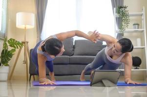 mettre en place de jeunes amies pratiquant le yoga à la maison via un cours en ligne avec un instructeur professionnel, un concept de sport et de mode de vie sain. photo