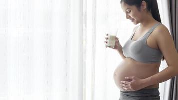 jeune femme enceinte buvant du lait à la maison, soins de santé et soins de grossesse photo