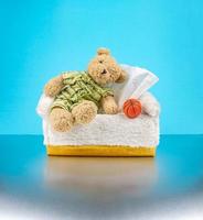 ours en peluche porte le pyjama et s'assoit sur la boîte à mouchoirs avec un ballon de basket à côté photo
