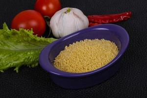 couscous cru dans le bol servi feuilles de salade, tomate et poivron photo