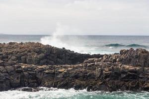 les vagues océaniques turbulentes avec de la mousse blanche battent les pierres côtières photo