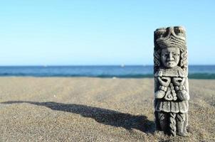 ancienne statue maya sur la plage de sable photo