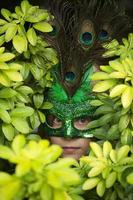 fille en masque culminant entre les feuilles vertes photo