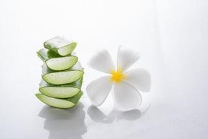 l'aloe vera et le plumeria décorés pour un spa ou une crème pour la peau sont placés sur fond blanc, l'aloe vera est des plantes vertes tropicales.cosmétiques de renouvellement bio naturel à l'aloe vera en tranches, concept de soins de la peau bio. photo