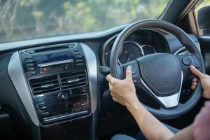 confiant et beau. vue arrière d'une jeune femme séduisante en tenue décontractée regardant par-dessus son épaule tout en conduisant une voiture. fille tenant la main sur le volant pour manipuler la voiture, concept de sécurité. photo