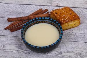 lait concentré dans le bol avec sinnamon et pâtisserie photo