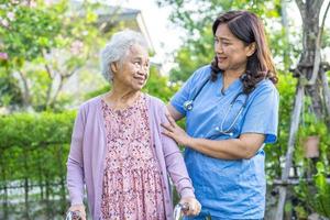 un médecin aide et soigne une vieille dame asiatique âgée ou âgée utilise un marcheur en bonne santé tout en marchant au parc pendant de joyeuses vacances fraîches photo