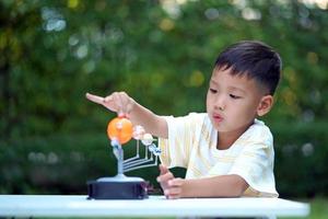 jouets du système solaire vivant pour garçon asiatique, équipement d'apprentissage à domicile, lors d'un nouveau changement normal après le coronavirus ou la situation de pandémie post-épidémie de covid-19 photo