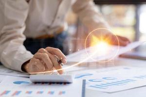 un homme d'affaires examine les données sur les documents financiers, les rapports financiers de l'entreprise, les graphiques montrant les données de croissance financière et numérique. le concept de gestion financière pour croître et être rentable. photo