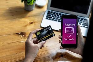 personne tenant un smartphone à l'écran d'un site de paiement en ligne, utilisant un smartphone pour payer des marchandises par carte de crédit en ligne. concept d'utilisation de smartphones pour payer des produits par carte de crédit. photo