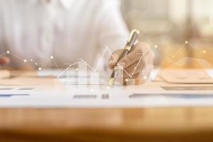 un homme d'affaires examine les données sur les documents financiers, les rapports financiers de l'entreprise, les graphiques montrant les données de croissance financière et numérique. le concept de gestion financière pour croître et être rentable. photo