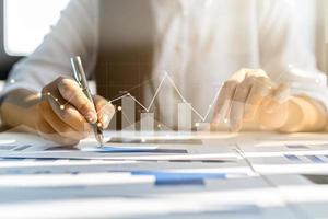 un homme d'affaires examine les données sur les documents financiers, les rapports financiers de l'entreprise, les graphiques montrant les données de croissance financière et numérique. le concept de gestion financière pour croître et être rentable. photo