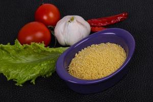 couscous cru dans le bol servi feuilles de salade, tomate et poivron photo
