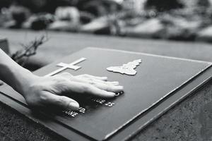 main de femme touchant la tombe en pierre noire. se remémorer, manquer, triste et perdre une personne dans la famille ou le concept de personnes importantes en noir et blanc photo