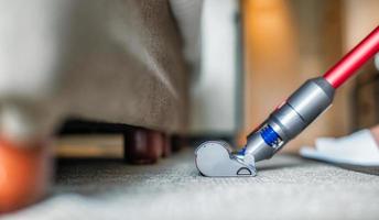 aspirateur moderne tout en passant l'aspirateur. femme à l'aide d'un aspirateur tout en nettoyant le tapis dans la maison. concept de nettoyage de maison. photo