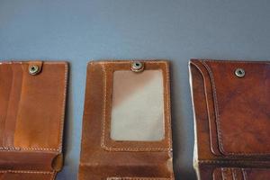 Trois portefeuilles vintage artisanaux en cuir marron sur fond gris photo