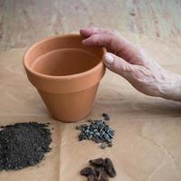 terre, cailloux et pot sur un papier brun. prêt à planter des graines de tomates à la maison. photo