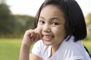 petite fille asiatique se détendre et sourire joyeusement dans le parc photo