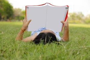 petite fille asiatique lisant un livre dans le parc photo